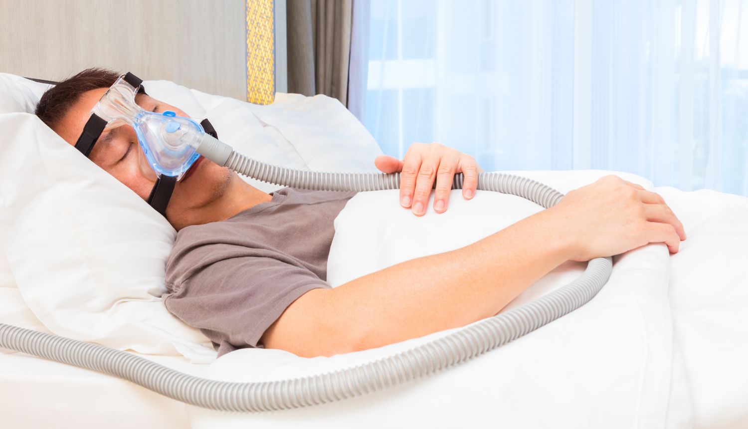 CPAP(シーパップ)をつけながら睡眠している男性